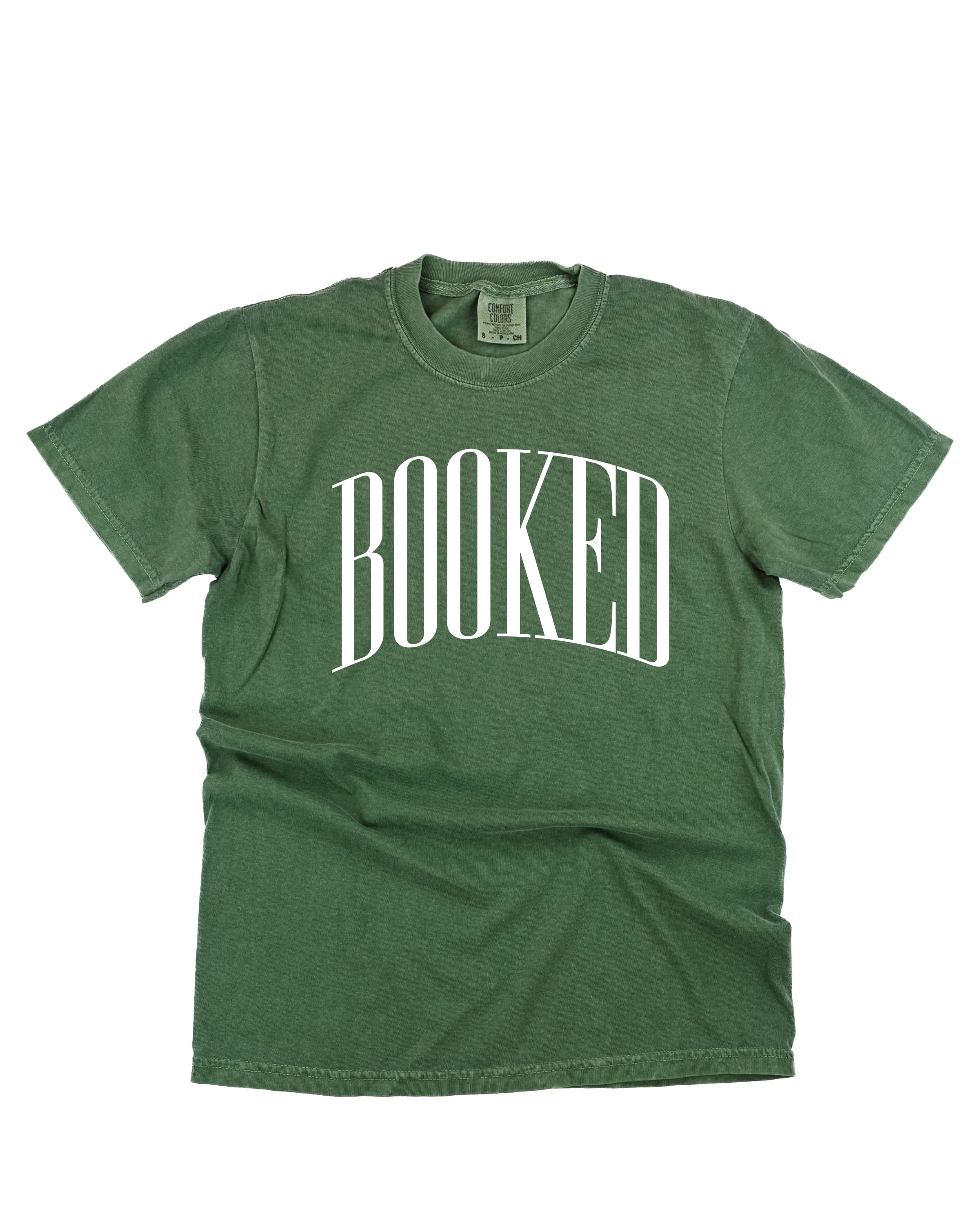 Comfort colors tee in hemp with 'BOOKED' graphic on chest, shown on flat lay – Little Mama Shirt Shop