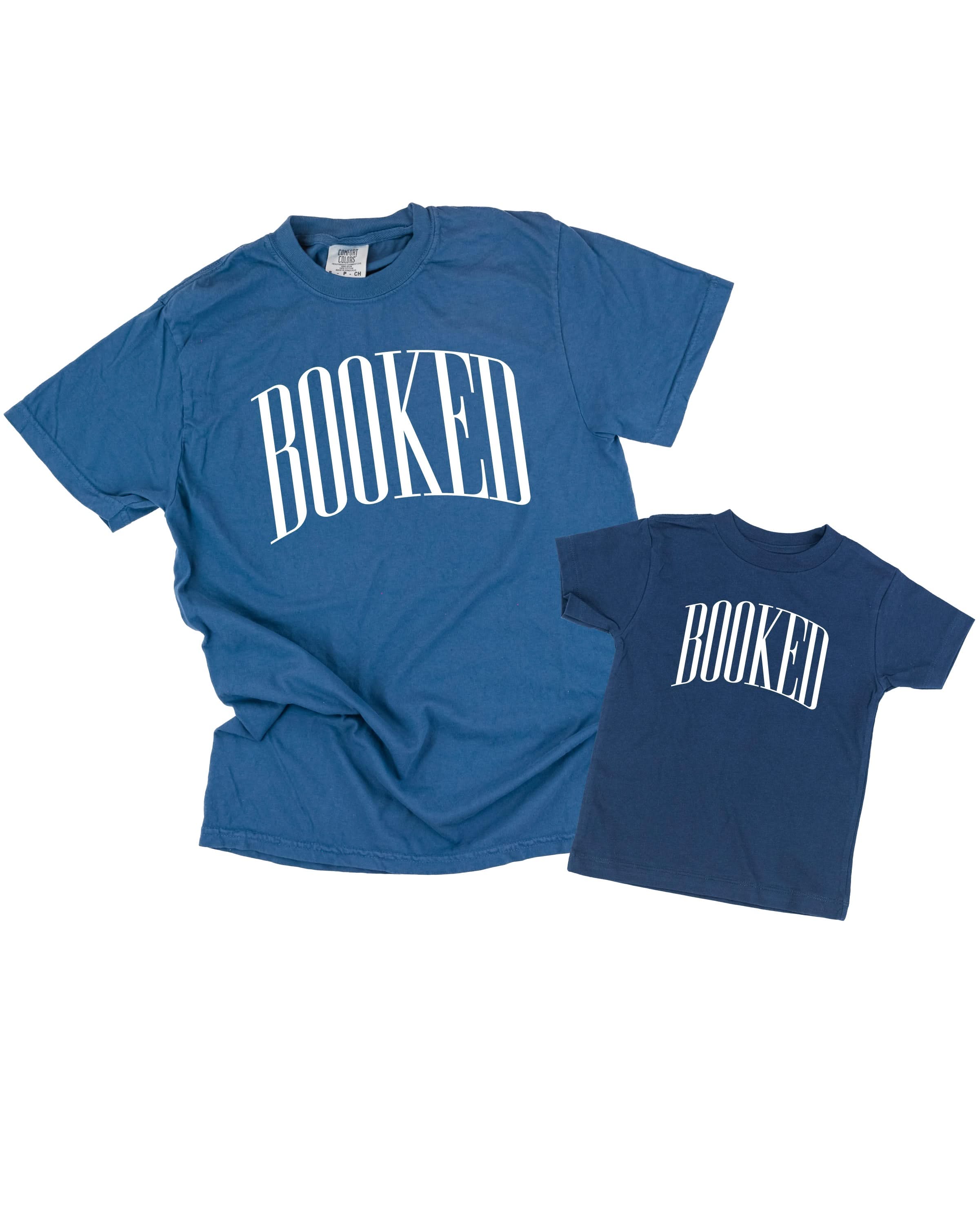 Two blue t-shirts with 'BOOKED' across the chest as a flat lay - Little Mama Shirt Shop