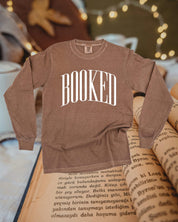 Long sleeve comfort colors tee in espresso with 'BOOKED' graphic on chest, shown on flat lay – Little Mama Shirt Shop