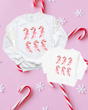 Adult and Child sweaters in white with 6 candy canes on chest, shown on flat lay – Little Mama Shirt Shop