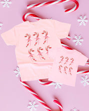 Adult and child tees in blossom and ballerina pink with 6 candy canes on chest, shown on flat lay – Little Mama Shirt Shop