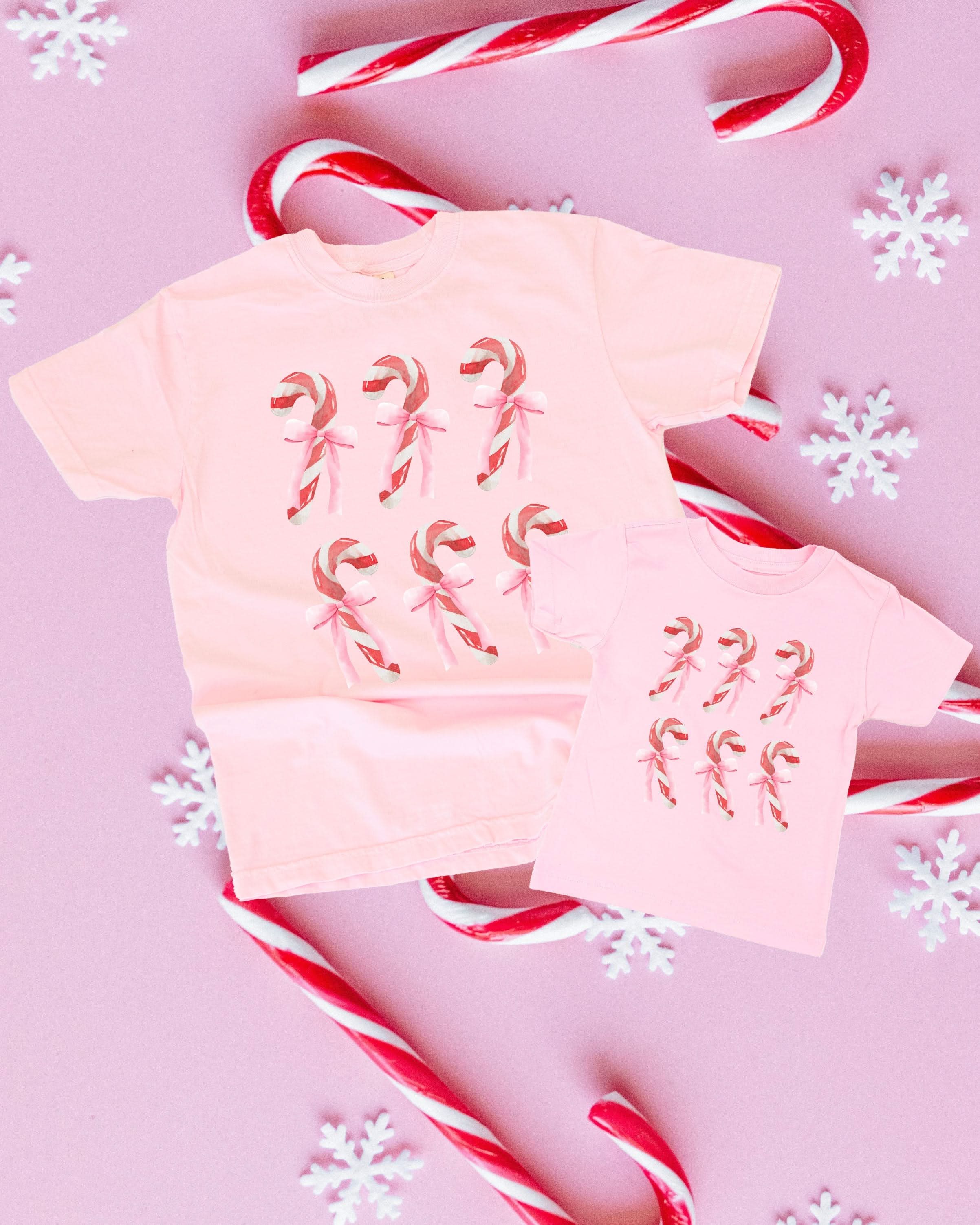 Adult and child tees in blossom and ballerina pink with 6 candy canes on chest, shown on flat lay – Little Mama Shirt Shop