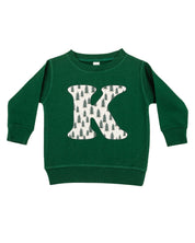 Child sweater in forest with Christmas patterned trees initial K on front, shown on flat lay – Little Mama Shirt Shop