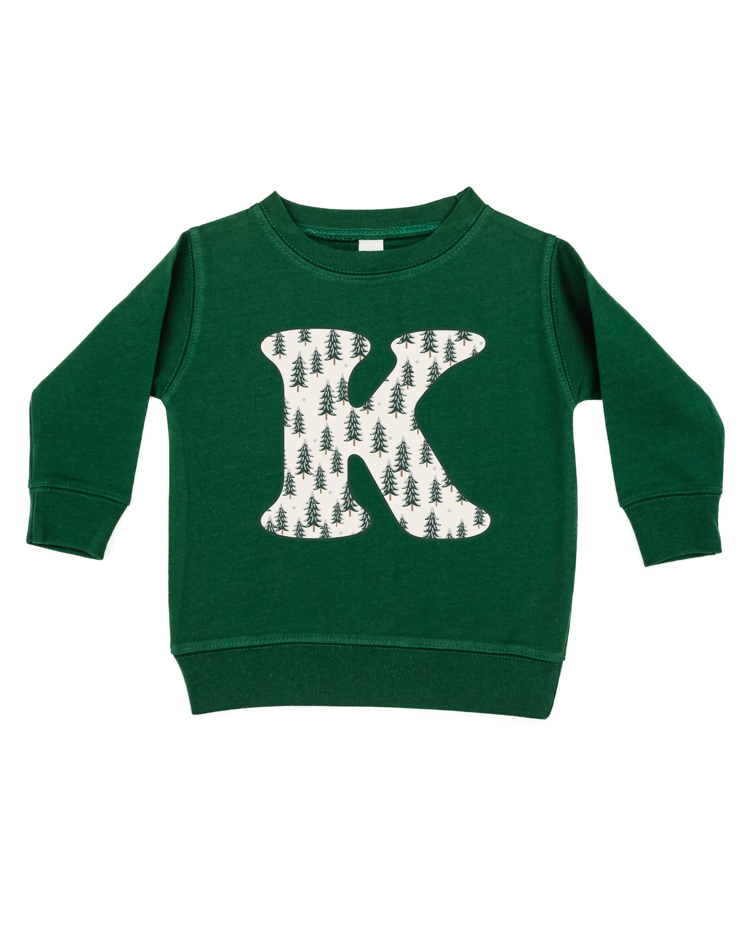 Child sweater in forest with Christmas patterned trees initial K on front, shown on flat lay – Little Mama Shirt Shop
