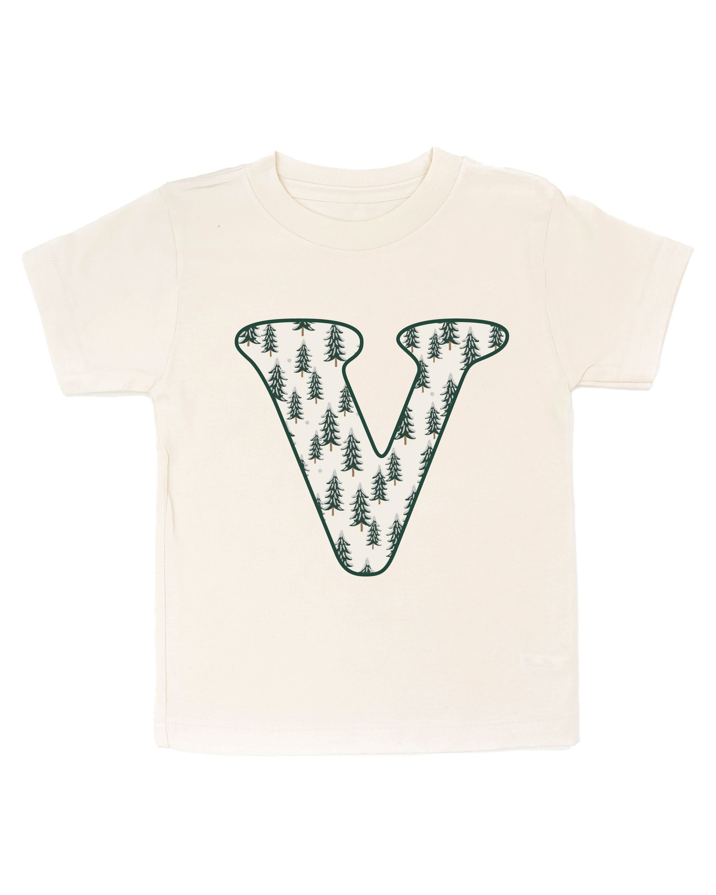 Child tee in natural with Christmas pattern trees with initial V on front, shown on flat lay – Little Mama Shirt Shop