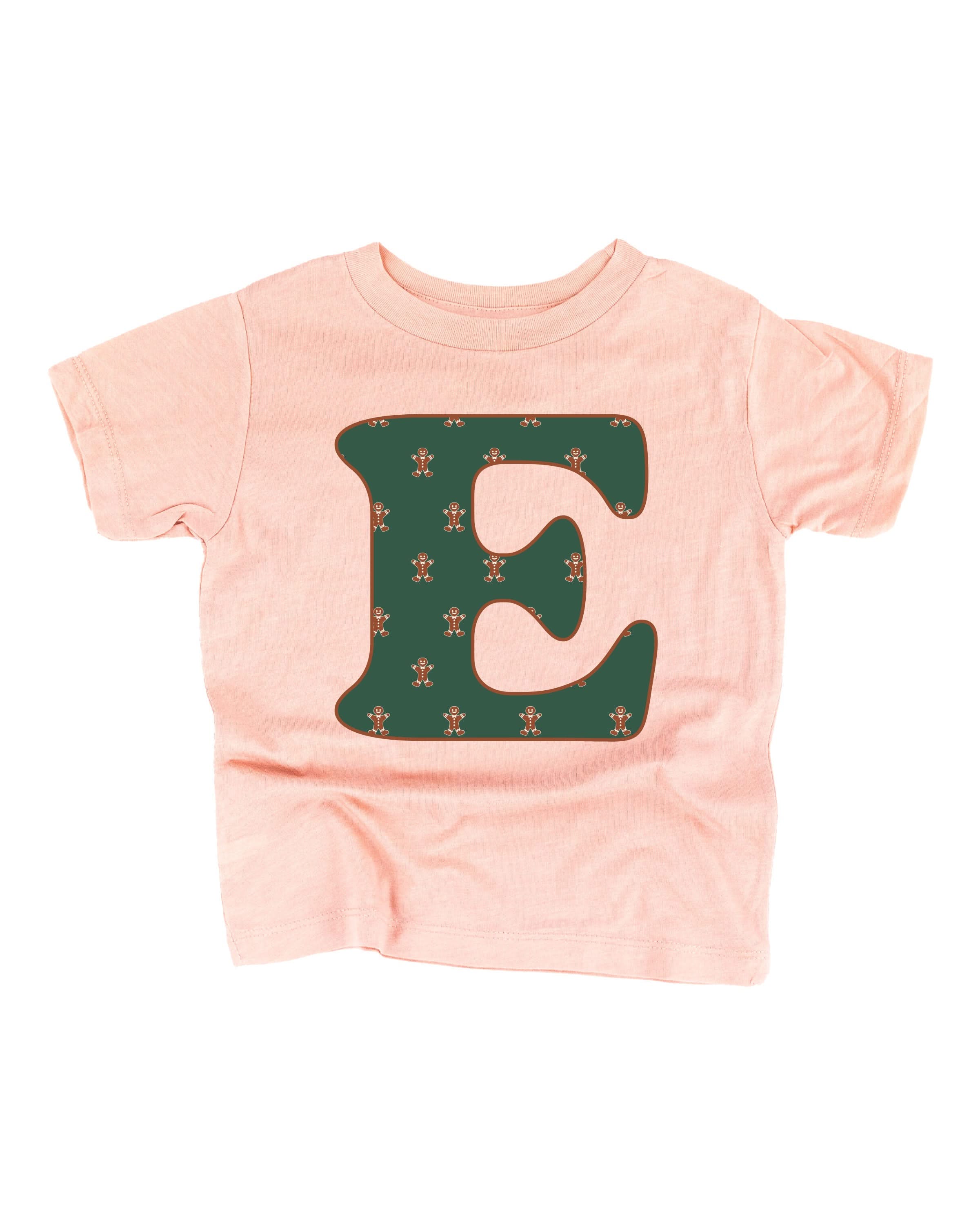 Child tee in blush with Christmas pattern gingerbread men with initial E on front, shown on flat lay – Little Mama Shirt Shop