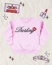 Child pink sweater with "Darling" script and lipstick kiss design, shown on flat lay  – Little Mama Shirt Shop