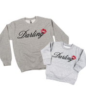 Adult and child gray sweaters with "Darling" script and lipstick kiss design, shown on flat lay  – Little Mama Shirt Shop