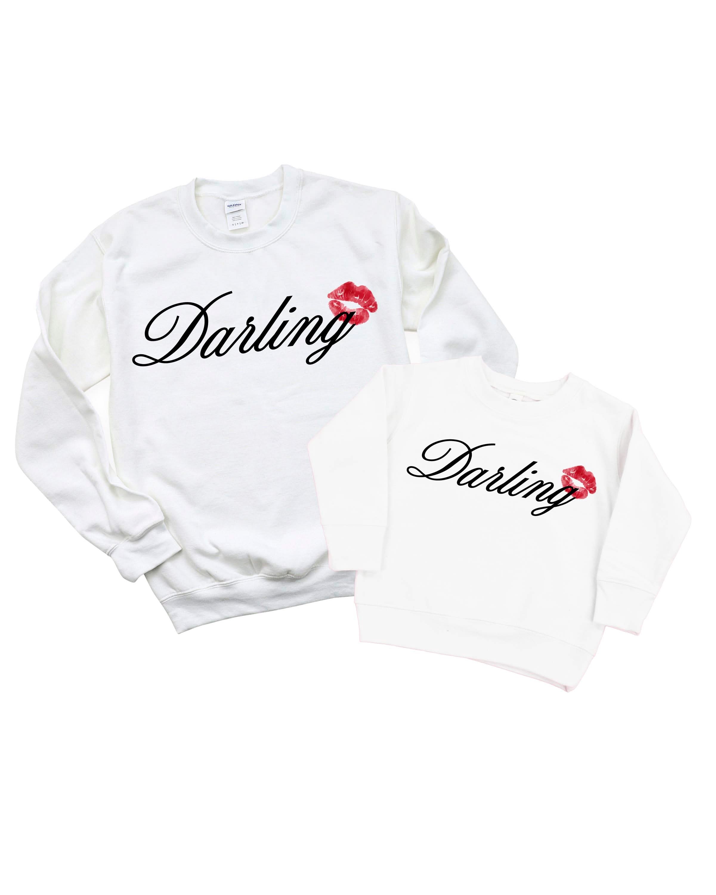Adult and child white sweaters with "Darling" script and lipstick kiss design, shown on flat lay  – Little Mama Shirt Shop