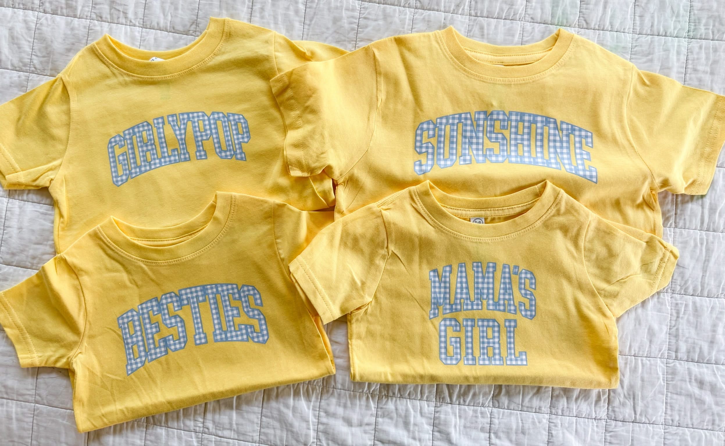 Multiple butter yellow girls shirts with blue gingham phrases showing different style options