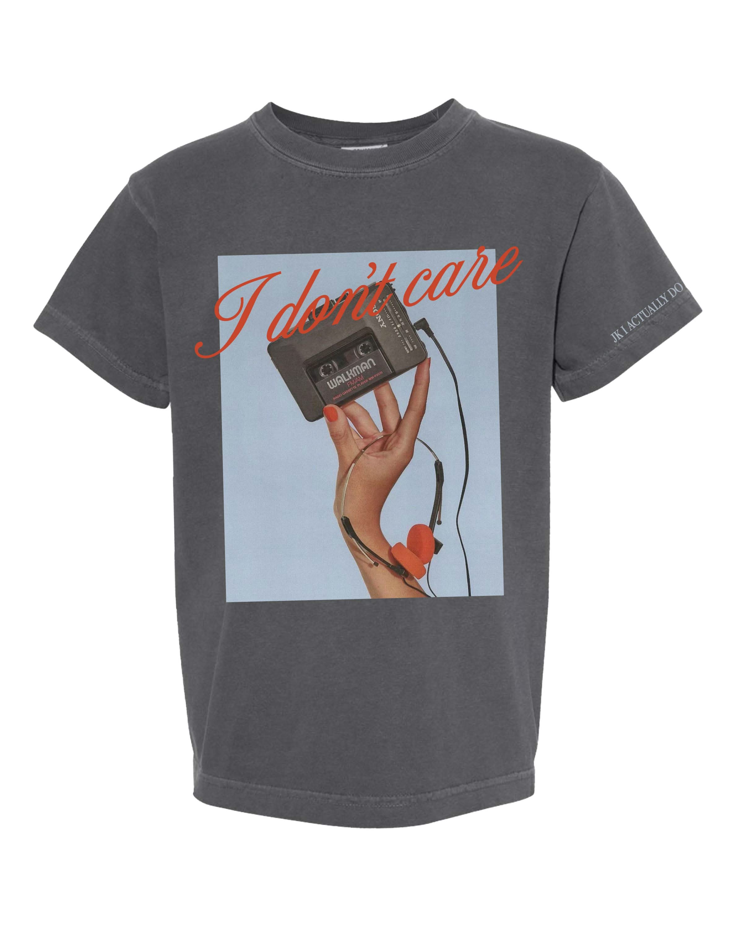 Child tee with "I Don't Care" retro cassette on front and "JK I Actually Do" text on sleeve, shown on flat lay  – Little Mama Shirt Shop