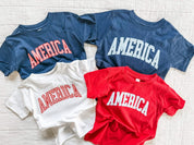 Kids AMERICA shirts in red, white, and blue with gingham lettering, laid out together for a classic summer look