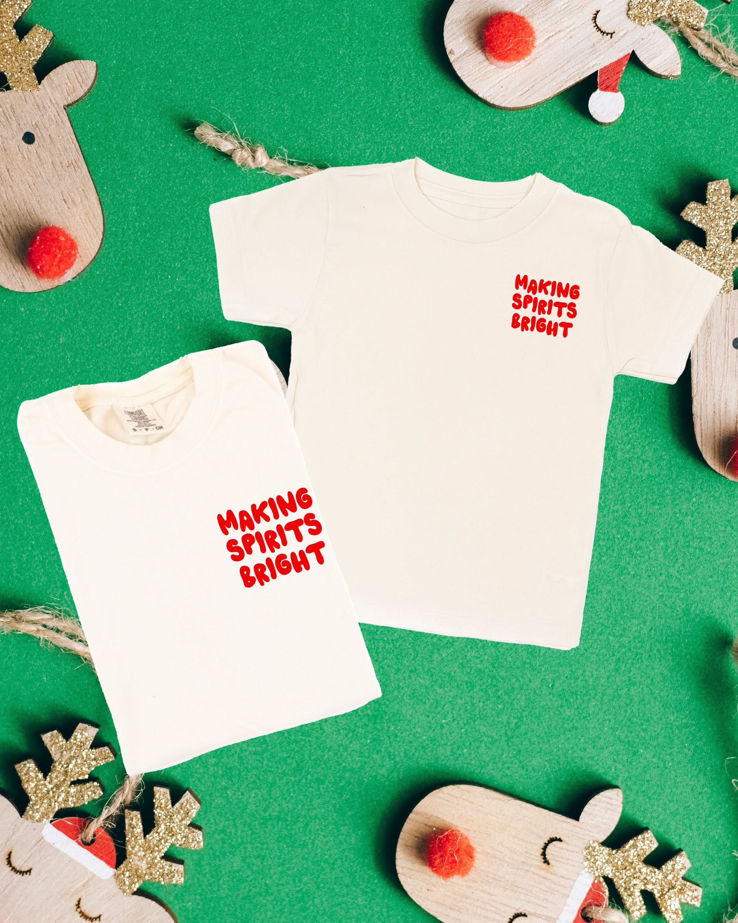 Adult ivory and child natural tees with 'making spirits bright' graphic on front, shown on flat lay – Little Mama Shirt Shop