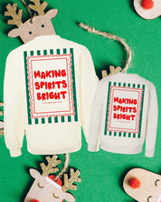 Adult off white and child natural sweaters with 'making spirits bright' graphic on back, shown on flat lay – Little Mama Shirt Shop