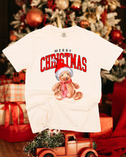 Adult comfort colors tee in ivory with merry Christmas teddy graphic, shown on flat lay – Little Mama Shirt Shop