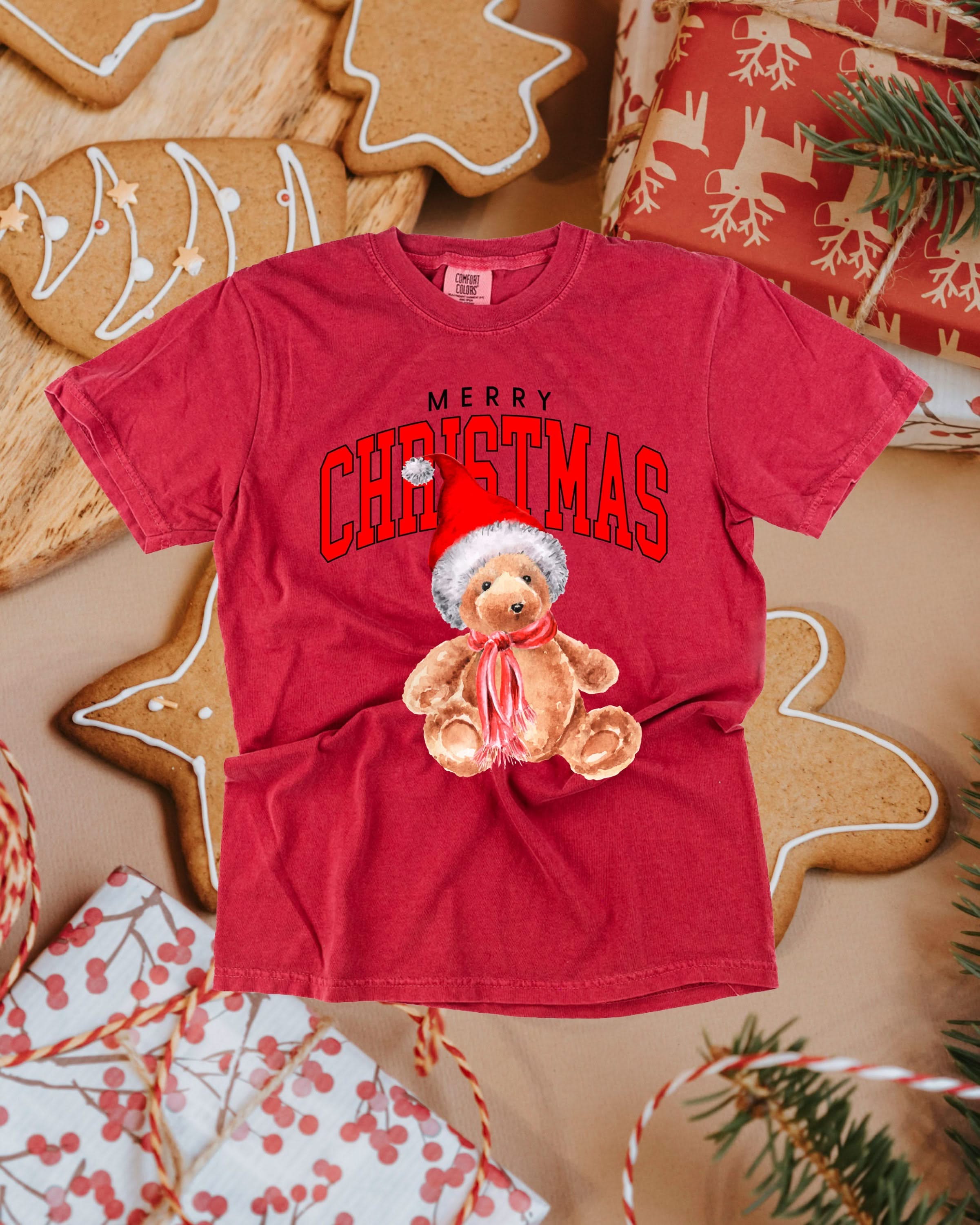 Adult comfort colors tee in crimson with merry Christmas teddy graphic, shown on flat lay – Little Mama Shirt Shop