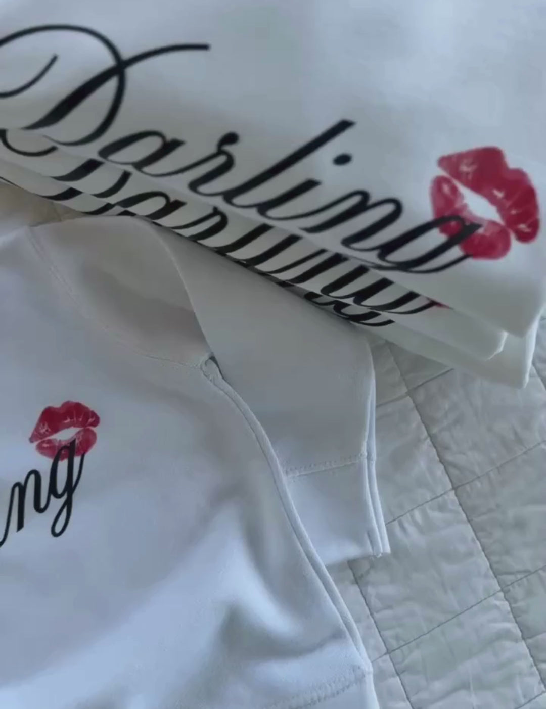 Video of child white sweater with "Darling" script and lipstick kiss design, shown on flat lay  – Little Mama Shirt Shop