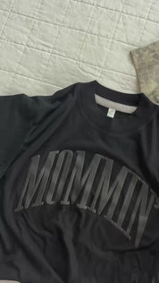 Video of adult boxy tee in black with 'mommin' printed on the front in puff print and camo tee with 'mother' printed on the front in puff print, seen on flat lay - Little Mama Shirt Shop
