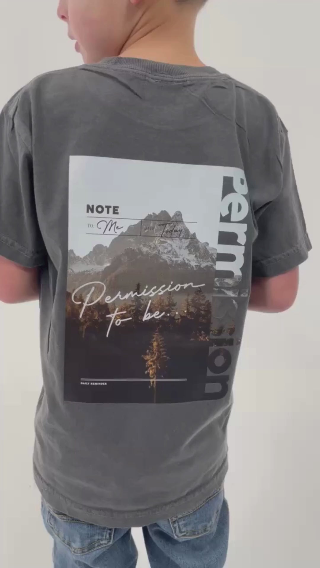 Video of pepper child comfort colors tee with permission to be mountain graphic on back and 'daily reminder' printed on front, seen on model - Little Mama Shirt Shop