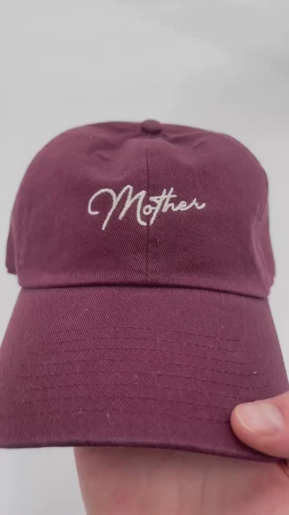 Video of maroon hat with cream embroidery "Mother", seen on flat lay - Little Mama Shirt Shop