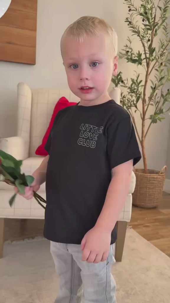 Video of Child tee in black with "Little Love Club" bubble letter text design on front left chest and back, shown on model – Little Mama Shirt Shop