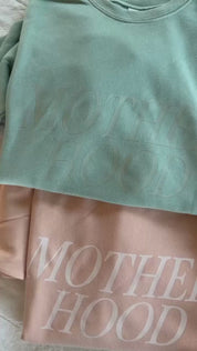 Video of adult fleece in army green, cream, blush, and mint with 'motherhood' printed on the front in tone on tone and 'someday we'll miss today' printed on sleeve, seen on flat lay - Little Mama Shirt Shop