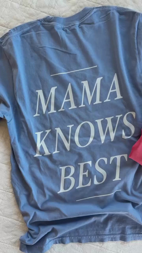 Video of adult tee in washed denim and watermelon with 'mama' printed on front with 'mama knows best' printed on the back, seen on flat lay - Little Mama Shirt Shop