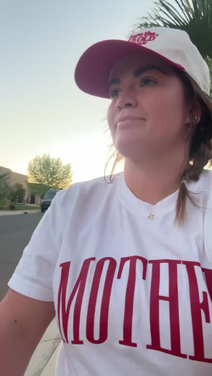 Video of white adult comfort colors tee with red 'mother' puff print across the front, seen on model - Little Mama Shirt Shop