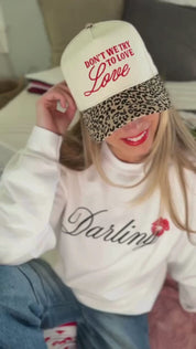 Video of adult cream and leopard hat with "Don't We Try To Love Love" design embroidered on front, shown on model – Little Mama Shirt Shop