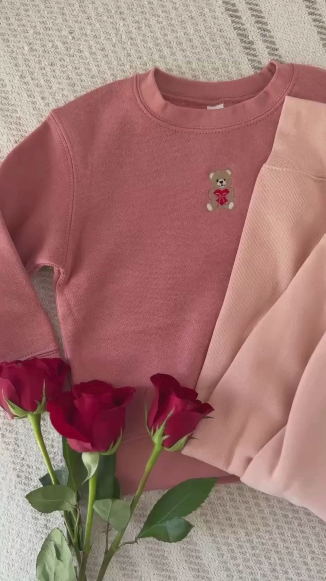 Video of child mauvelous and adult pink sweaters with valentine's teddy Embroidery on front, shown on flat lay  – Little Mama Shirt Shop