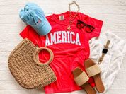 Red AMERICA shirt styled with woven accessories and sandals for an easy summer outfit idea