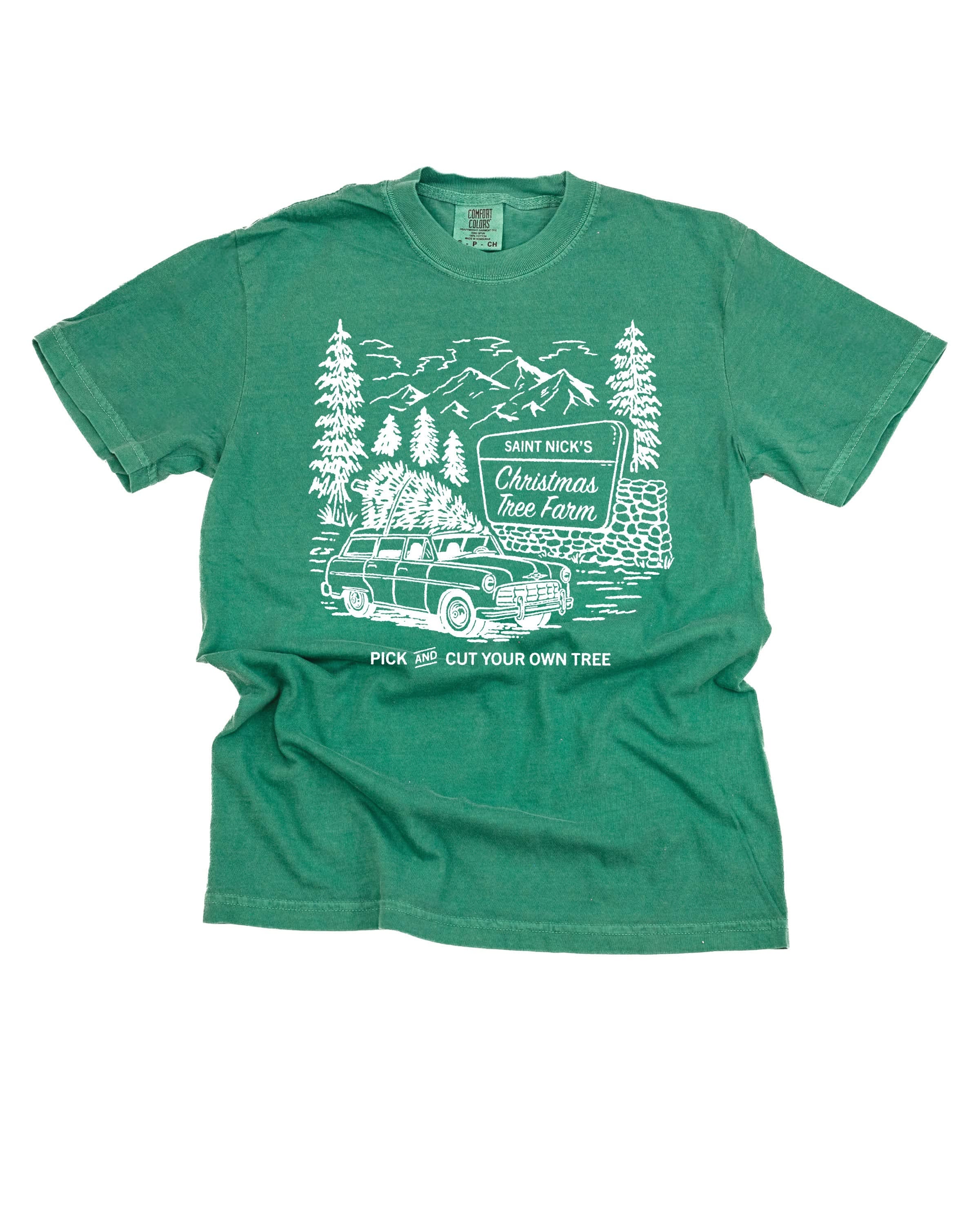 Comfort Colors Tee in light green with St. Nick's Christmas Tree Farm graphic on the front, shown on flay lay – Little Mama Shirt Shop